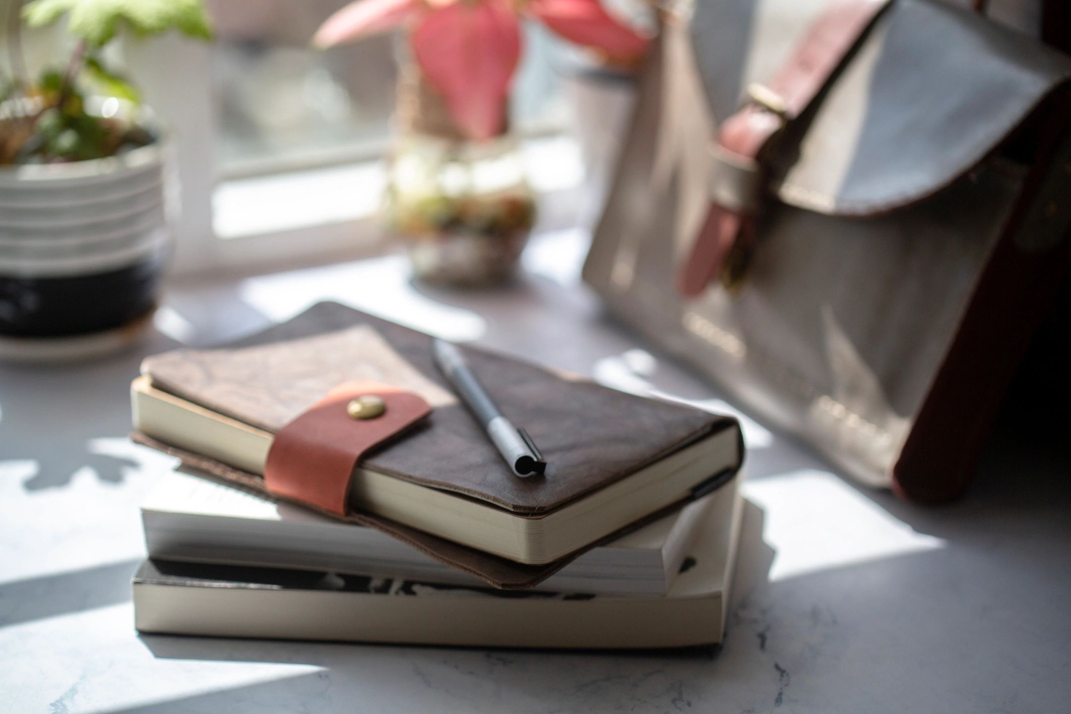 Notebook and briefcase on a table near a window